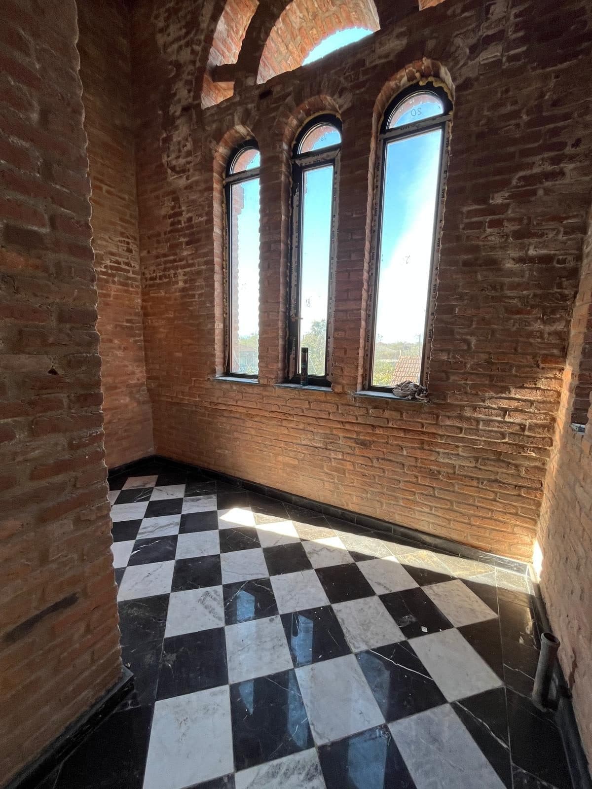 Checkered marble floor and brick arched windows in one of the towers